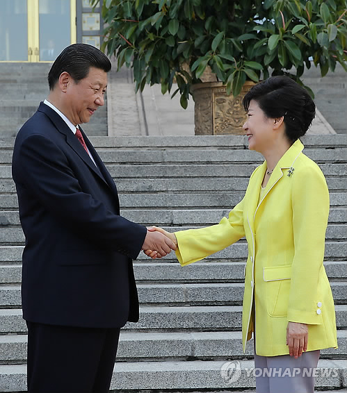 资料图片：去年6月朴槿惠总统对中国进行国事访问并出席在人民大会堂东门外广场举行的欢迎仪式，图中两国领导人正亲切握手。（韩联社）